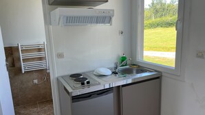 Een compacte keuken met een inbouwfornuis, een spoelbak en een raam met uitzicht op de omgeving.