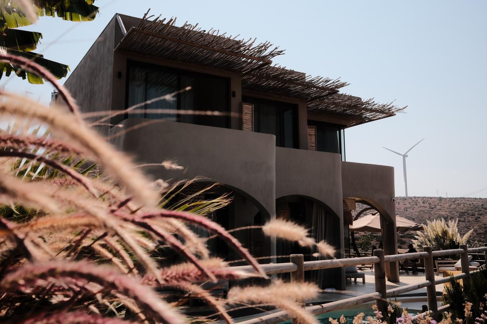 A modern building with a flat roof, large windows, and a pool area with a wooden fence.