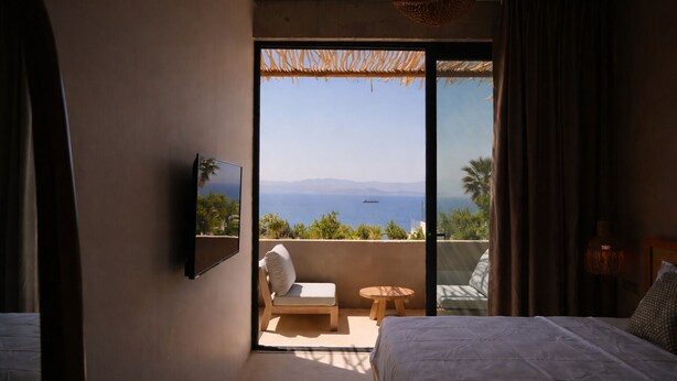 A bedroom with a bed, a TV, a balcony with a chair and table, and a view of the sea. - No.908 Sunset Hotel (Cesme)