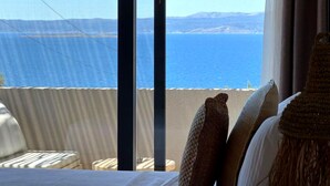 A room with a view of the sea, a bed, and a window with curtains. - No.908 Sunset Hotel (Cesme)