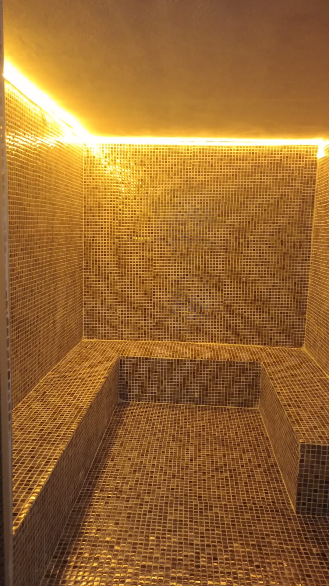 Una habitación con piso de baldosas, un banco y un escalón.