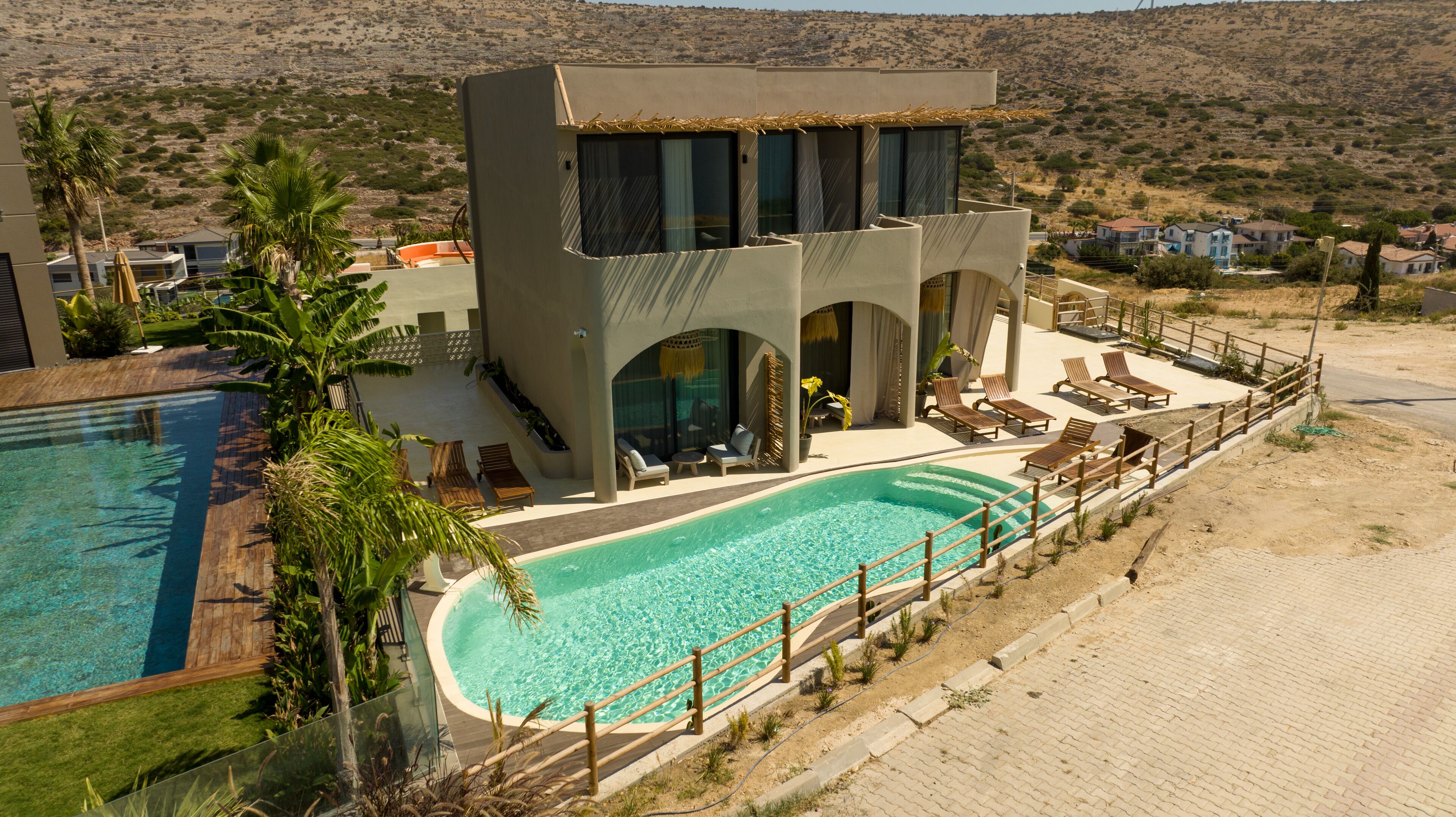 A modern resort with a pool, lounge chairs, and a mountainous backdrop.