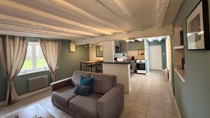 Een moderne woonkamer met een bank, een salontafel en uitzicht op de keuken en eetruimte.