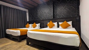 Une chambre d’hôtel avec deux lits, chacun agrémenté de draps blancs et de touches de couleur orange. La chambre est dotée d’une tête de lit en bois foncé et d’un mur orné de motifs.