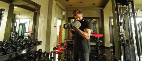 A gym with various weightlifting equipment, including dumbbells and a bench press.
