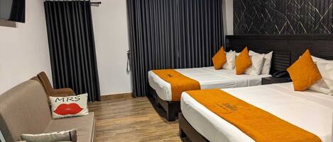 Une chambre d’hôtel avec deux lits, un canapé et un fauteuil.