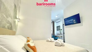 Ett hotellrum med en säng, kuddar, handdukar, ett skrivbord och en tv.