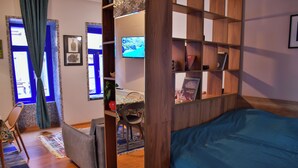A bedroom with a wooden bed, a desk with a chair, a television, and a bookshelf. - The Librarians' Flat with Balcony (Tbilisi)
