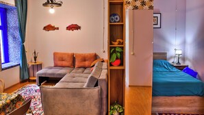 A compact room with a bed, a small table, and a shelf with decorative items. - The Librarians' Flat with Balcony (Tbilisi)
