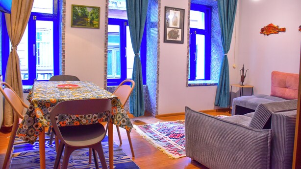 A dining area with a table set for four, two chairs, a patterned tablecloth, and a blue curtain. - The Librarians' Flat with Balcony (Tbilisi)