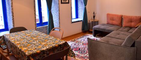 Ein gemütliches Zimmer mit Esstisch, einer Couch und einem gemusterten Teppich.