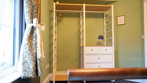 Et værelse med en seng, en garderobe med spejl og et vindue med gardiner.
