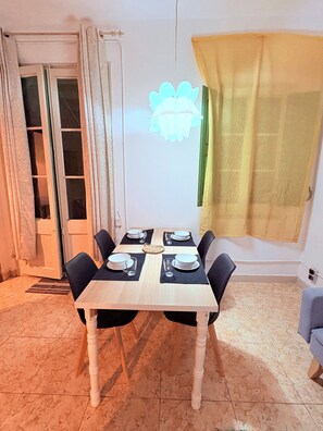 A dining area with a table for four, set with black chairs and a woven placemat.
