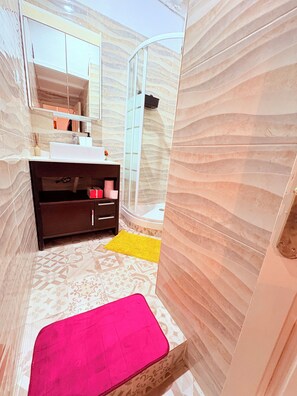 Bathroom features a white sink, mirror, and glass shower enclosure with a tub.