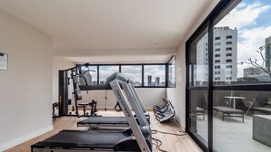 Ein modernes Fitnessstudio mit Trainingsgeräten, großen Fenstern und Blick auf die Stadt.