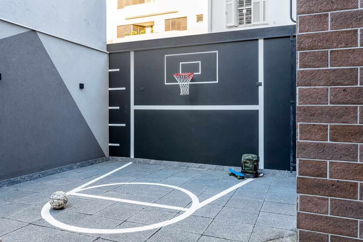 Una cancha de baloncesto con un aro, una pelota de fútbol y un monopatín.