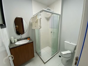 Un baño moderno con ducha de vidrio, lavamanos blanco y un inodoro.