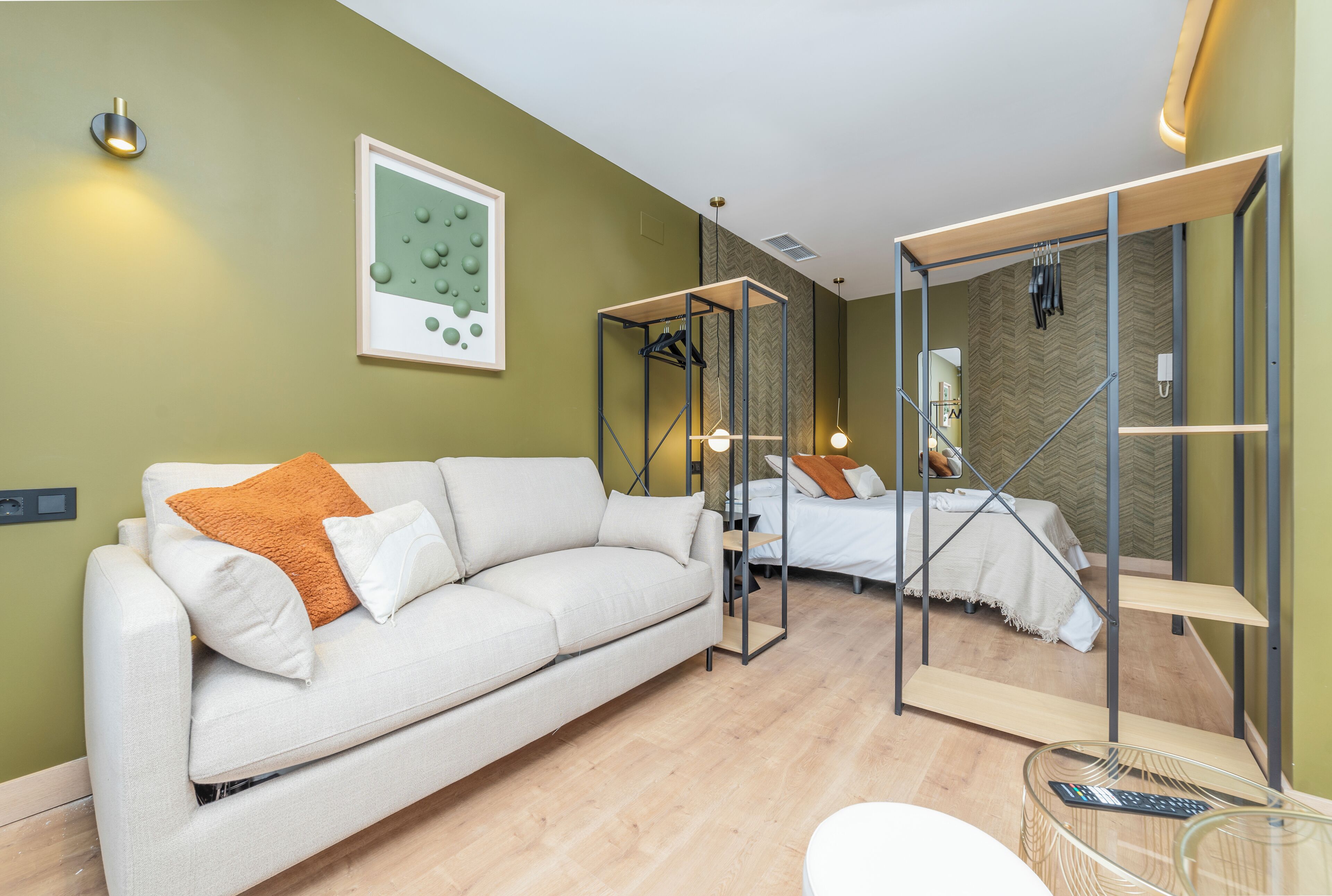 Een moderne, goed verlichte kamer met een bank, een bed en een glazen bijzettafeltje.