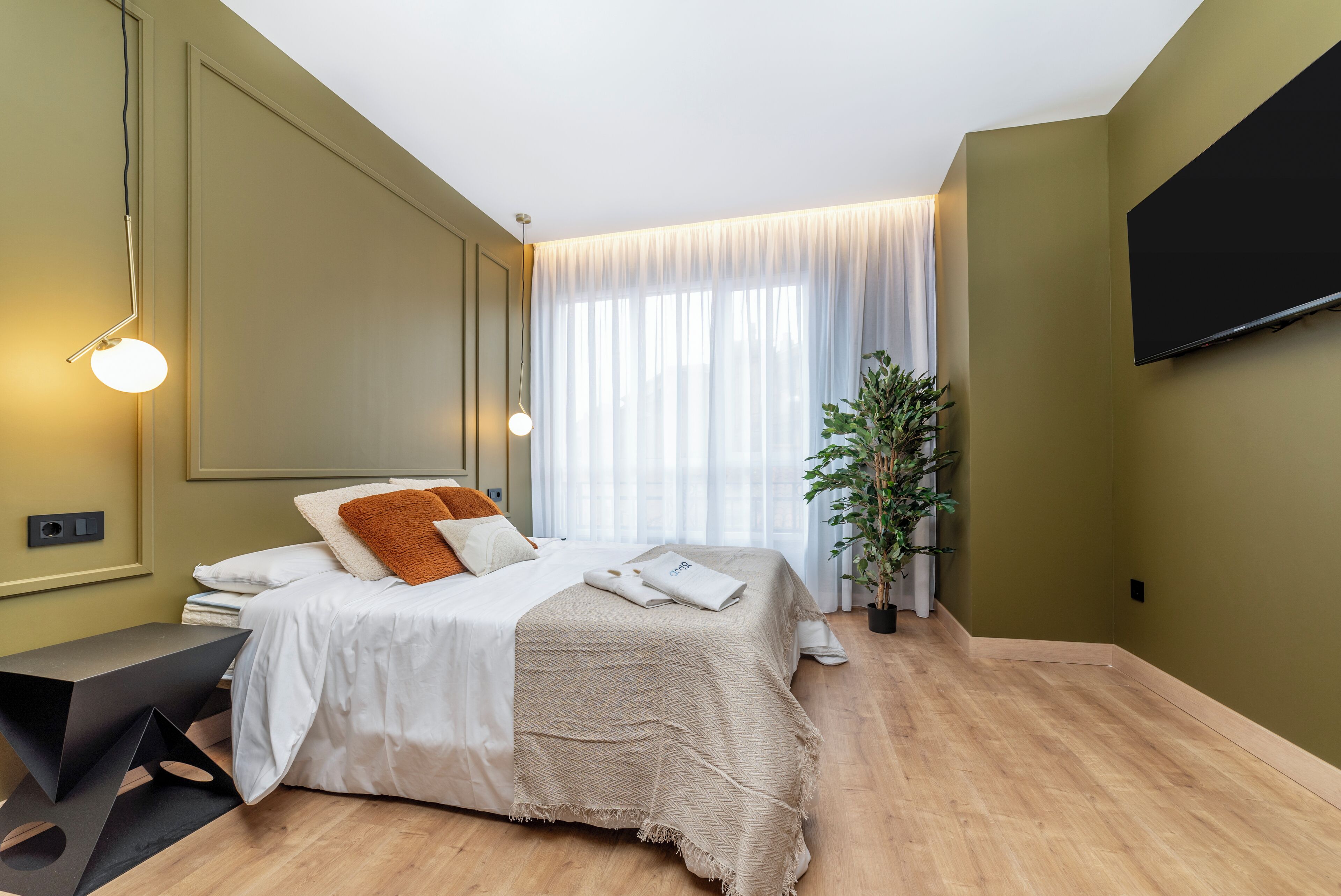 Une chambre moderne avec un lit, une table de chevet et une grande fenêtre avec des rideaux.