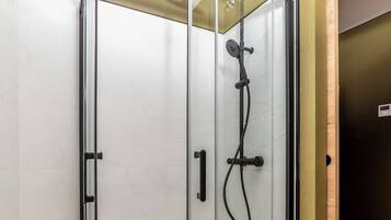 A glass-enclosed shower with a showerhead and control panel.