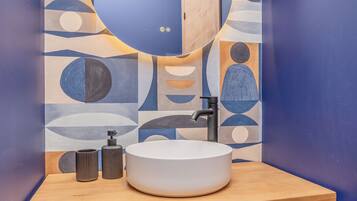 A bathroom with a modern design, featuring a sink, mirror, and a wall with abstract patterns.
