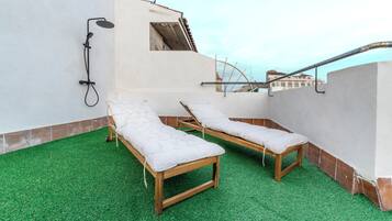 A rooftop terrace with two wooden sun loungers and a built-in shower.