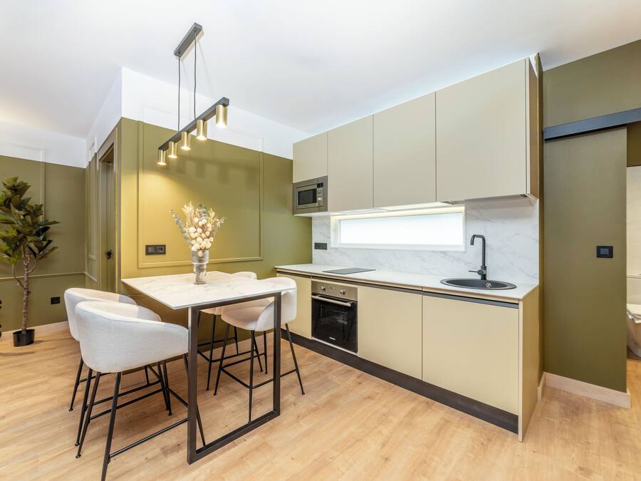 A modern kitchen with a central island, bar stools, a microwave, oven, and a sink.