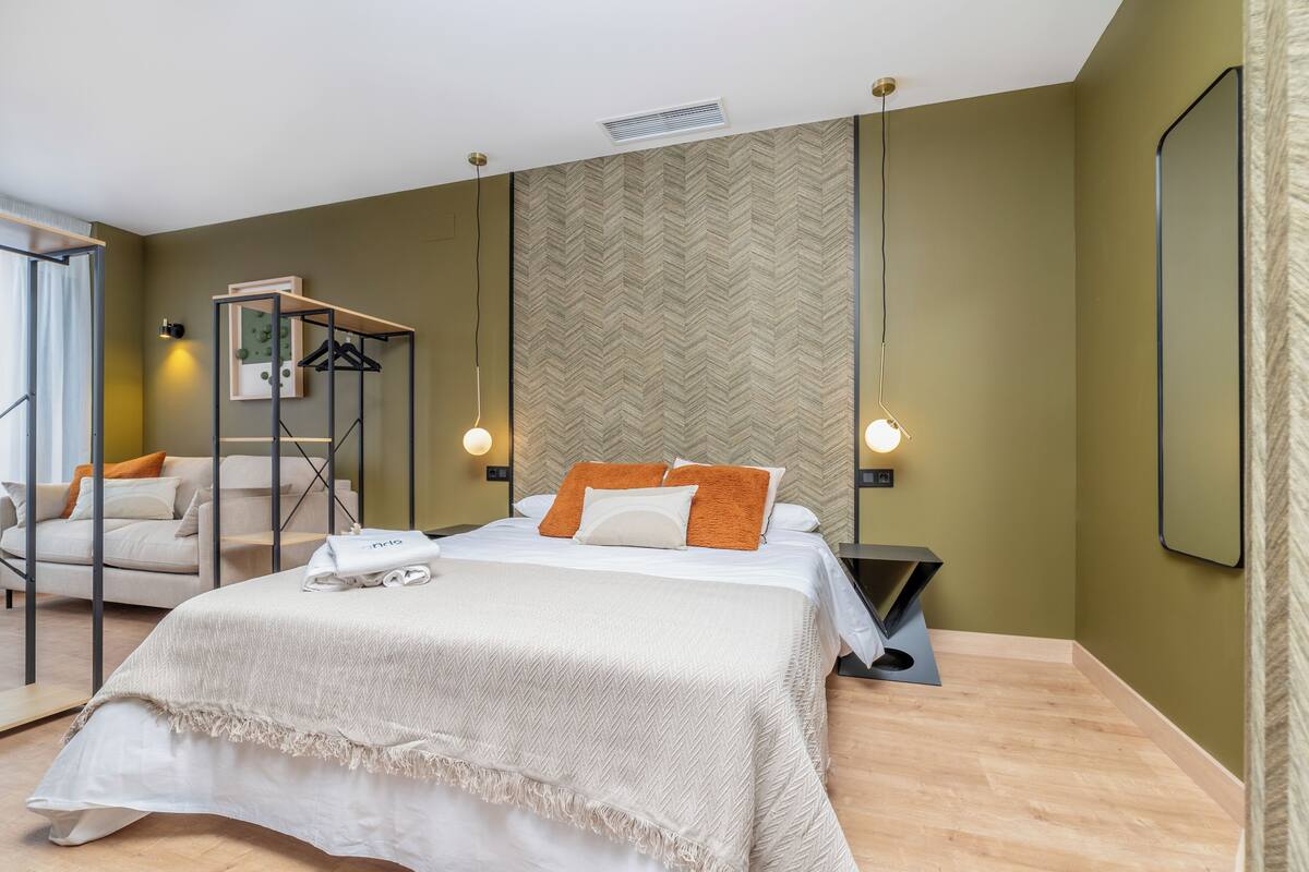 Une chambre d’hôtel moderne équipée d’un lit, d’un coin salon et d’une armoire.