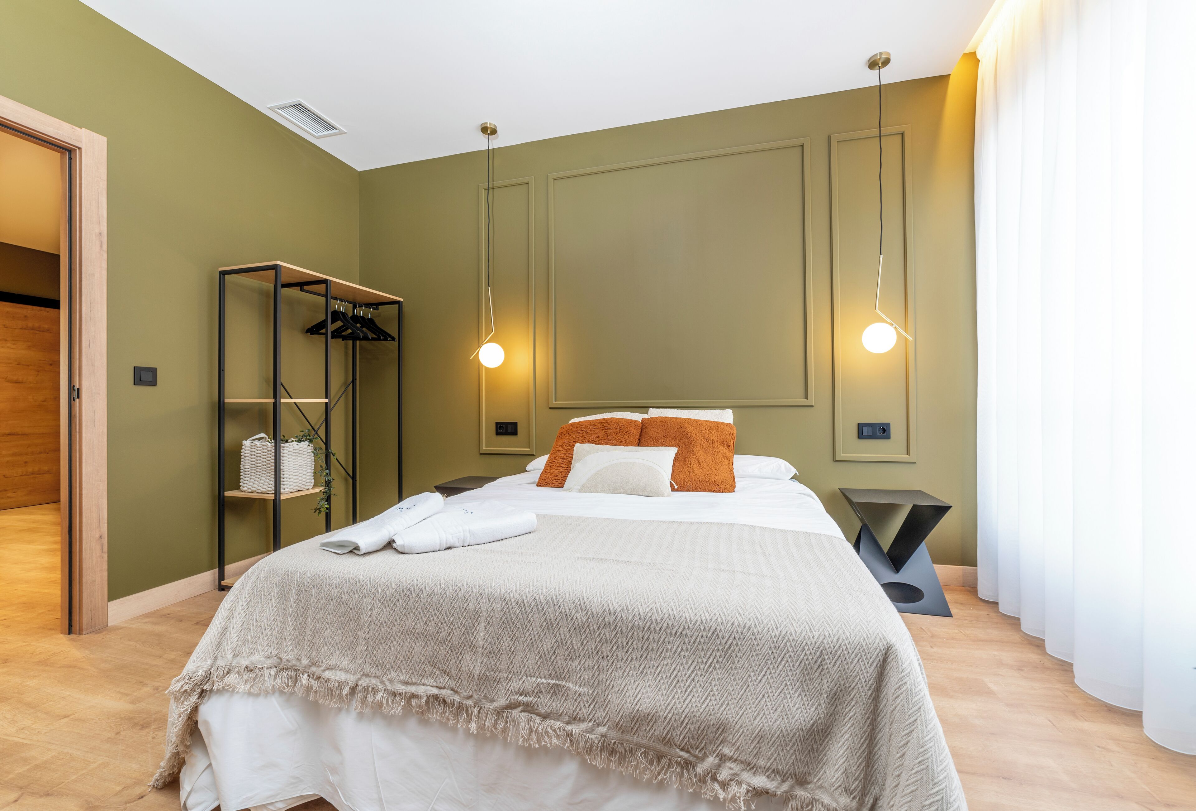 Una habitación de hotel con una cama, un armario y una mesita de noche.