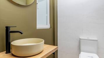 A bathroom with a round sink, black faucet, and a toilet.