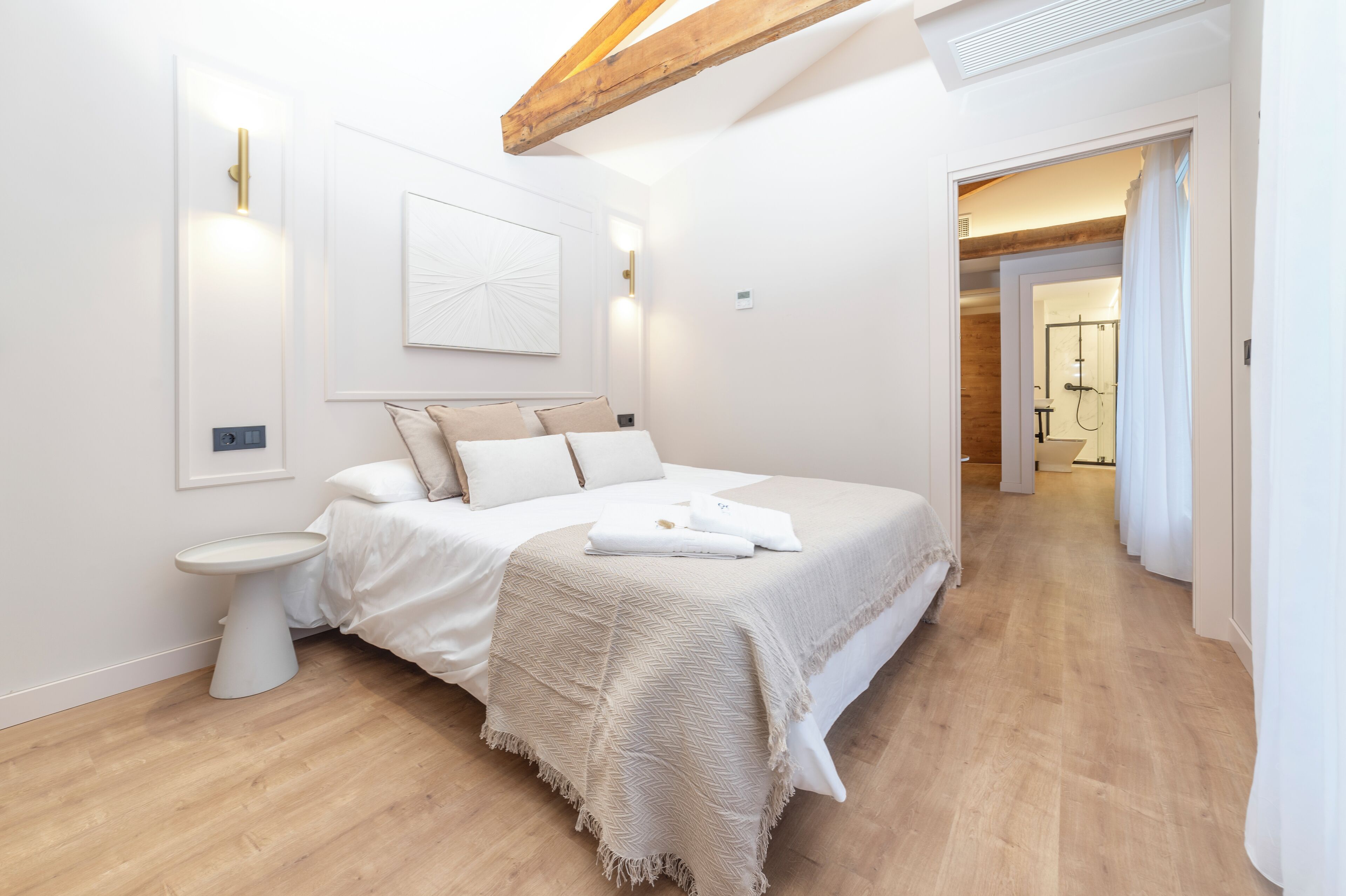 Camera moderna con un letto grande, un comodino e un punto luce a parete.