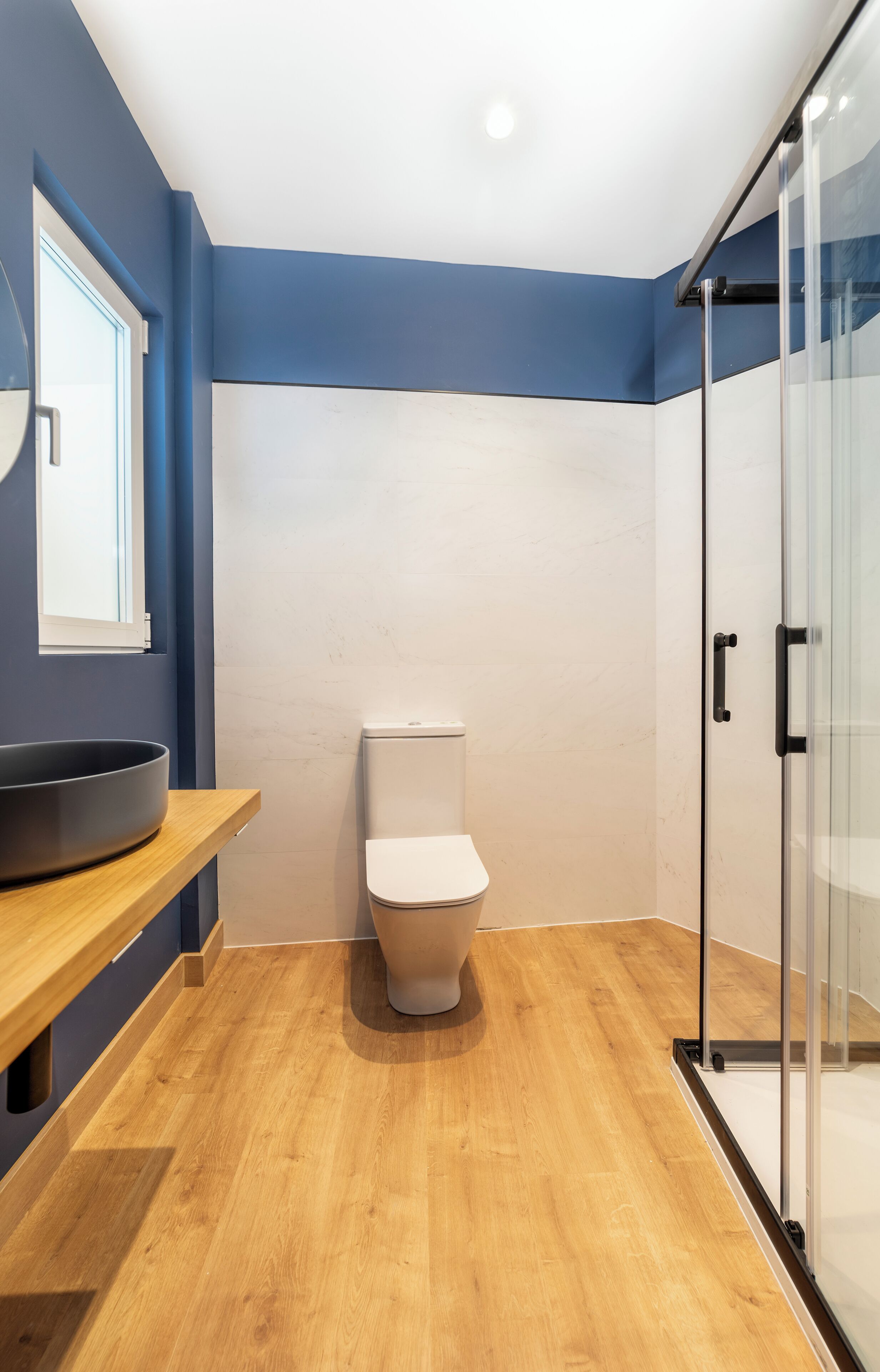 Une salle de bain moderne avec des toilettes, une douche à parois de verre et un meuble-lavabo en bois.