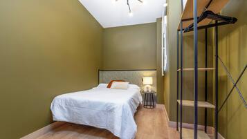 Un dormitorio con cama, lámpara de noche y suelo de madera.