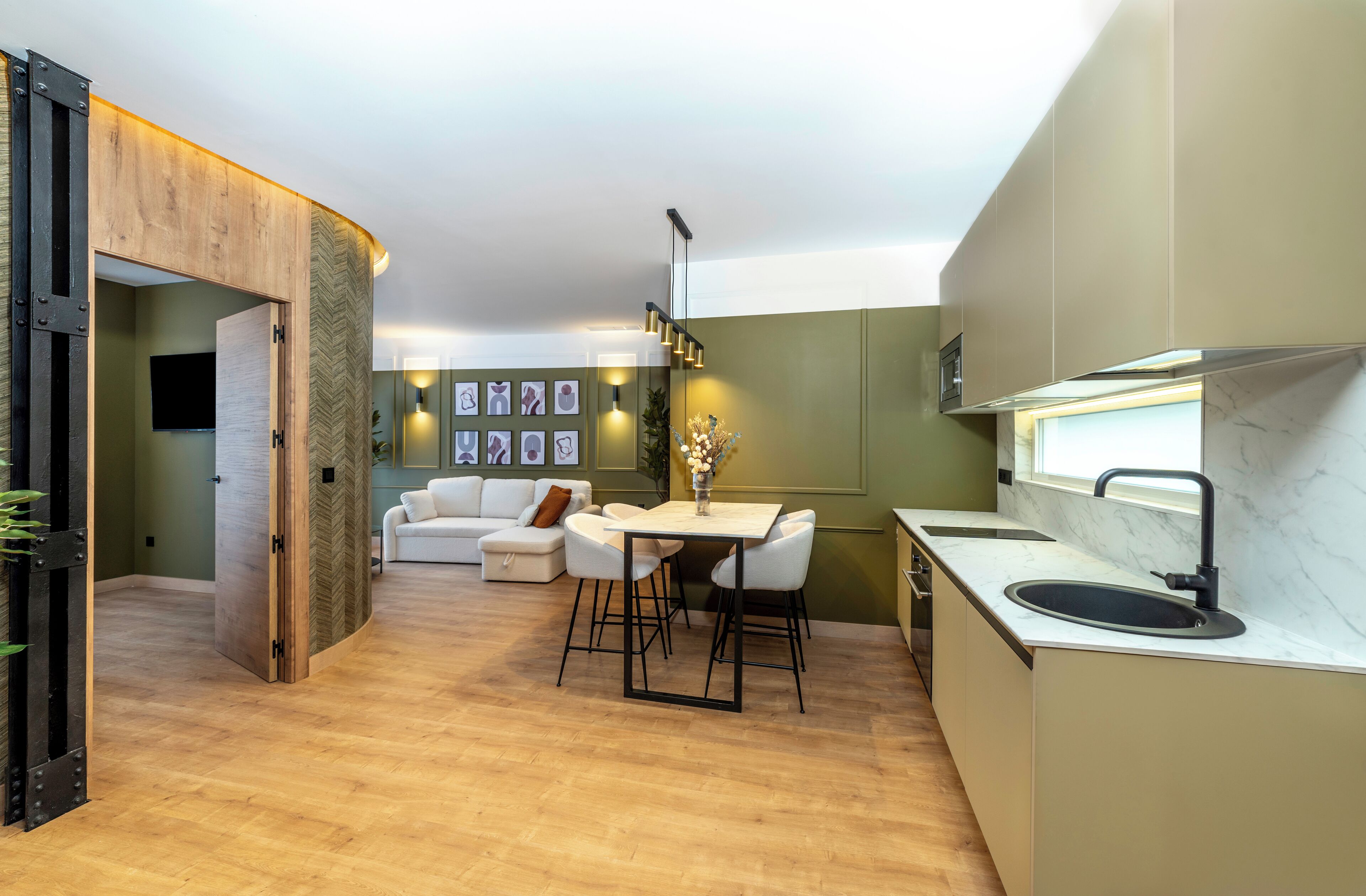 Una cocina moderna con encimera de mármol, un lavamanos y un comedor con mesa y sillas blancas.