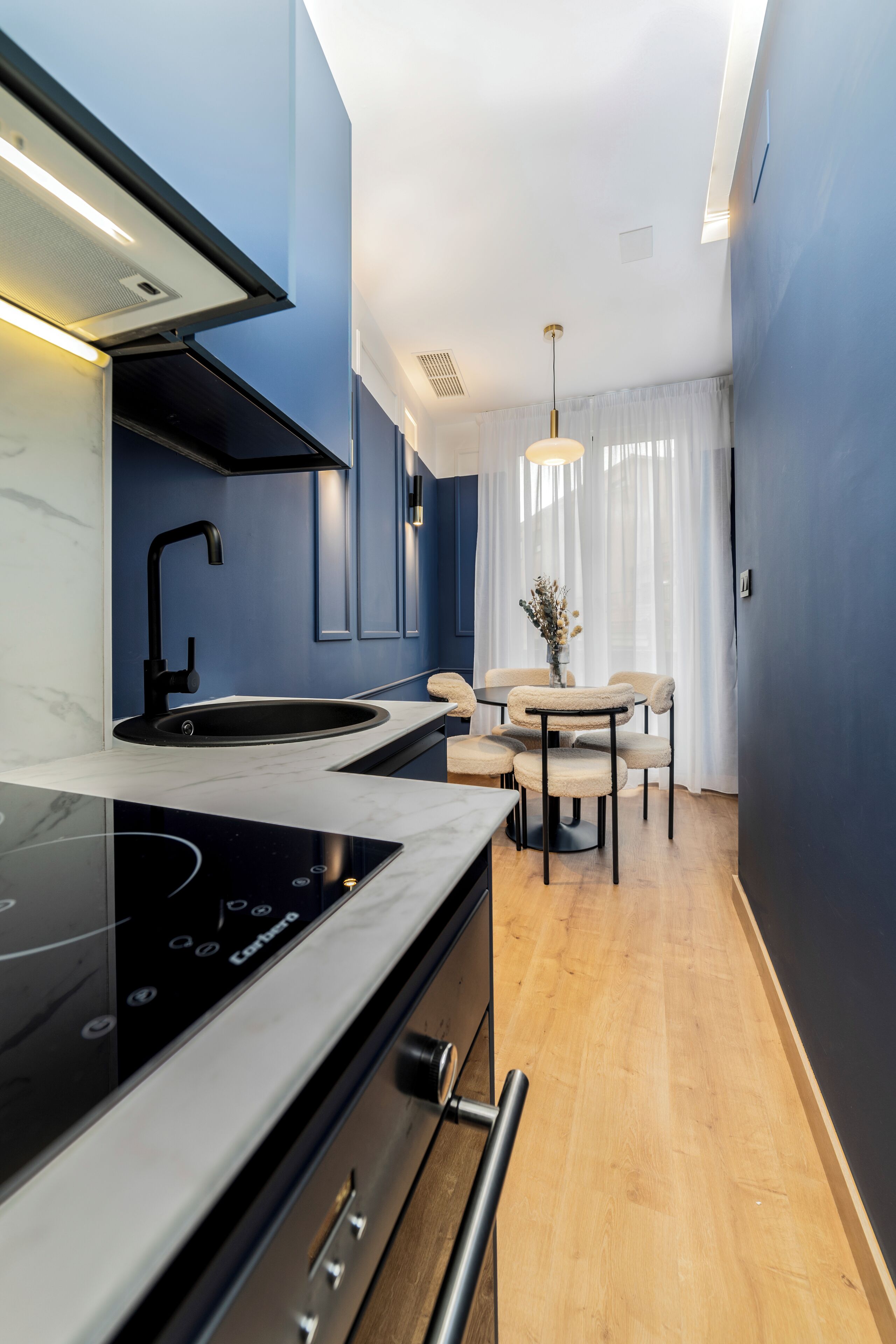 A compact kitchen with a modern stove, a sink, and a dining area with a table and chairs.