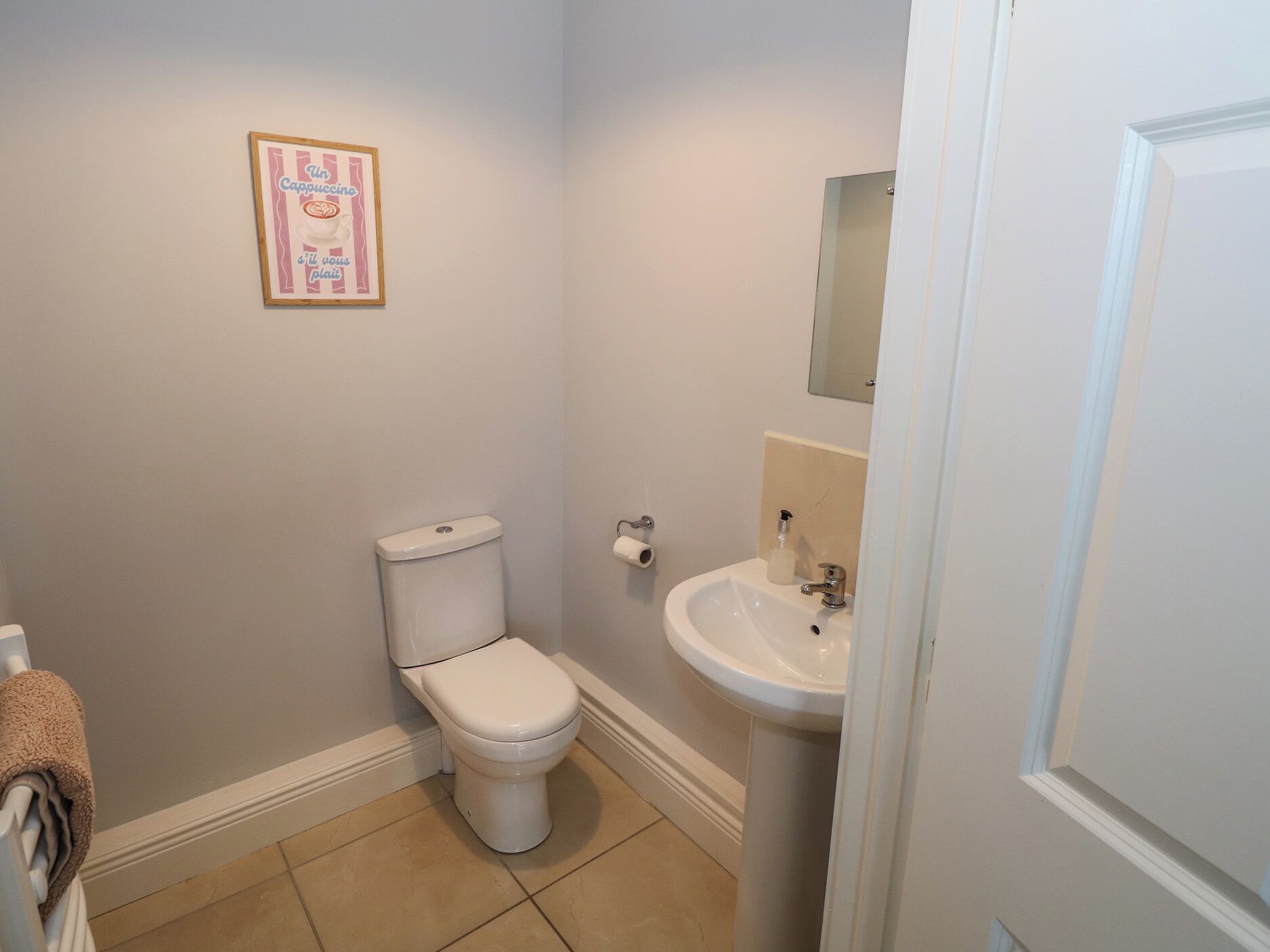 A bathroom with a toilet, sink, and a framed picture on the wall.