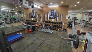 A gym with various exercise equipment, including dumbbells, benches, and weight machines. - Glow Inn HomeStay (Varanasi)