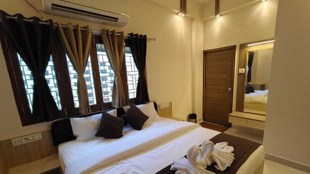 A hotel room with a large bed, a mirror, and an air conditioning unit. - Glow Inn HomeStay (Varanasi)