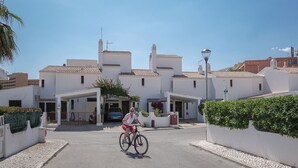 A residential street with white houses, a cyclist, and a clear blue sky. - Quentao Red Villa, Quarteira, Algarve (Quarteira)