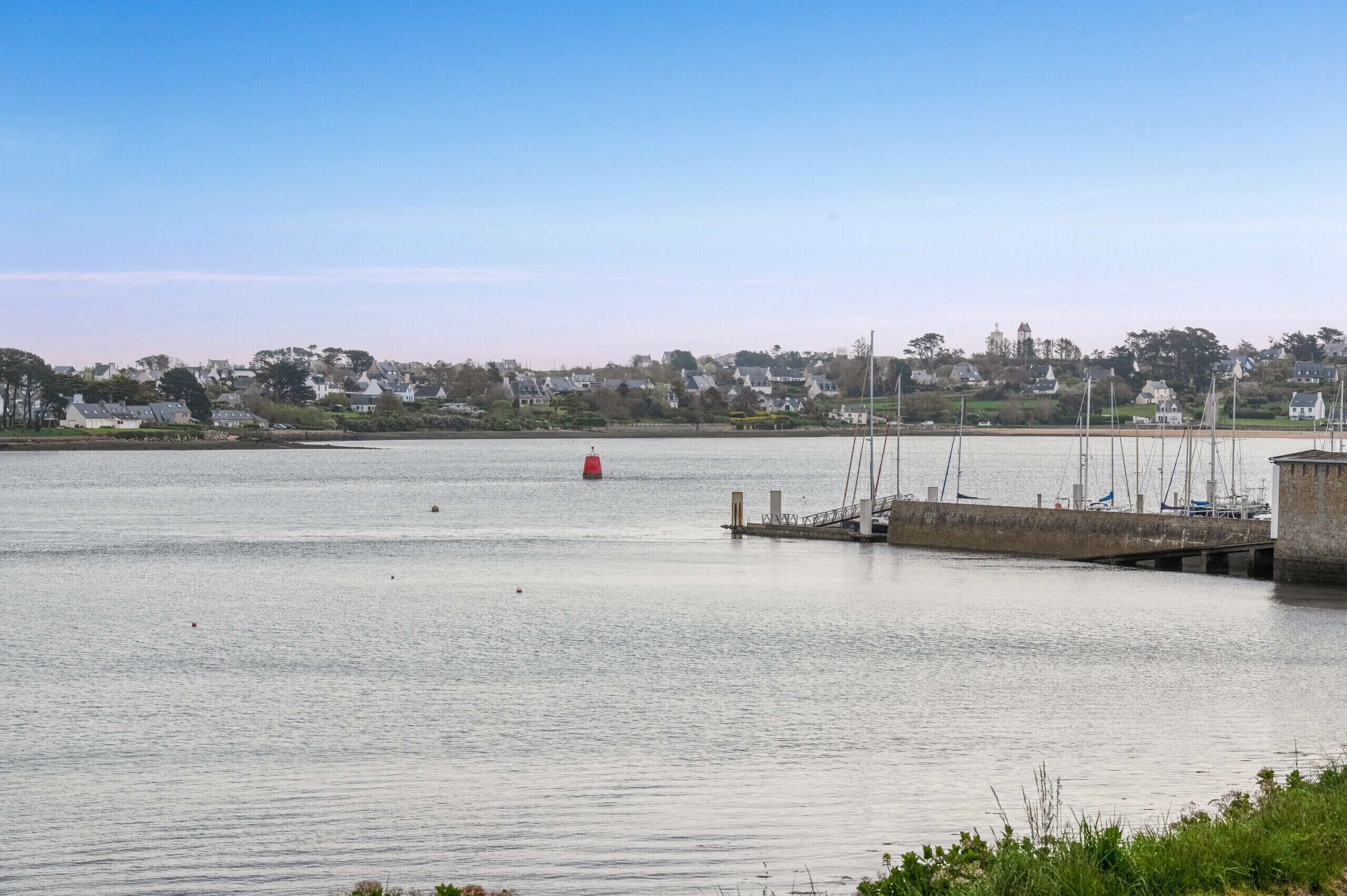 Un rivage paisible, avec une jetée et des voiliers.