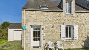 A stone house with a garage, a small porch with two chairs, and a clear blue sky. - House in La Torche - Large garden for 4 (Saint-Jean-Trolimon)
