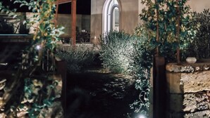 A nighttime view of a building with a glass enclosure, surrounded by greenery and a stone wall. - masseria casina fiocca (Vernole)