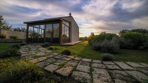 A modern house with a glass facade, a stone pathway, and a garden. - masseria casina fiocca (Vernole)