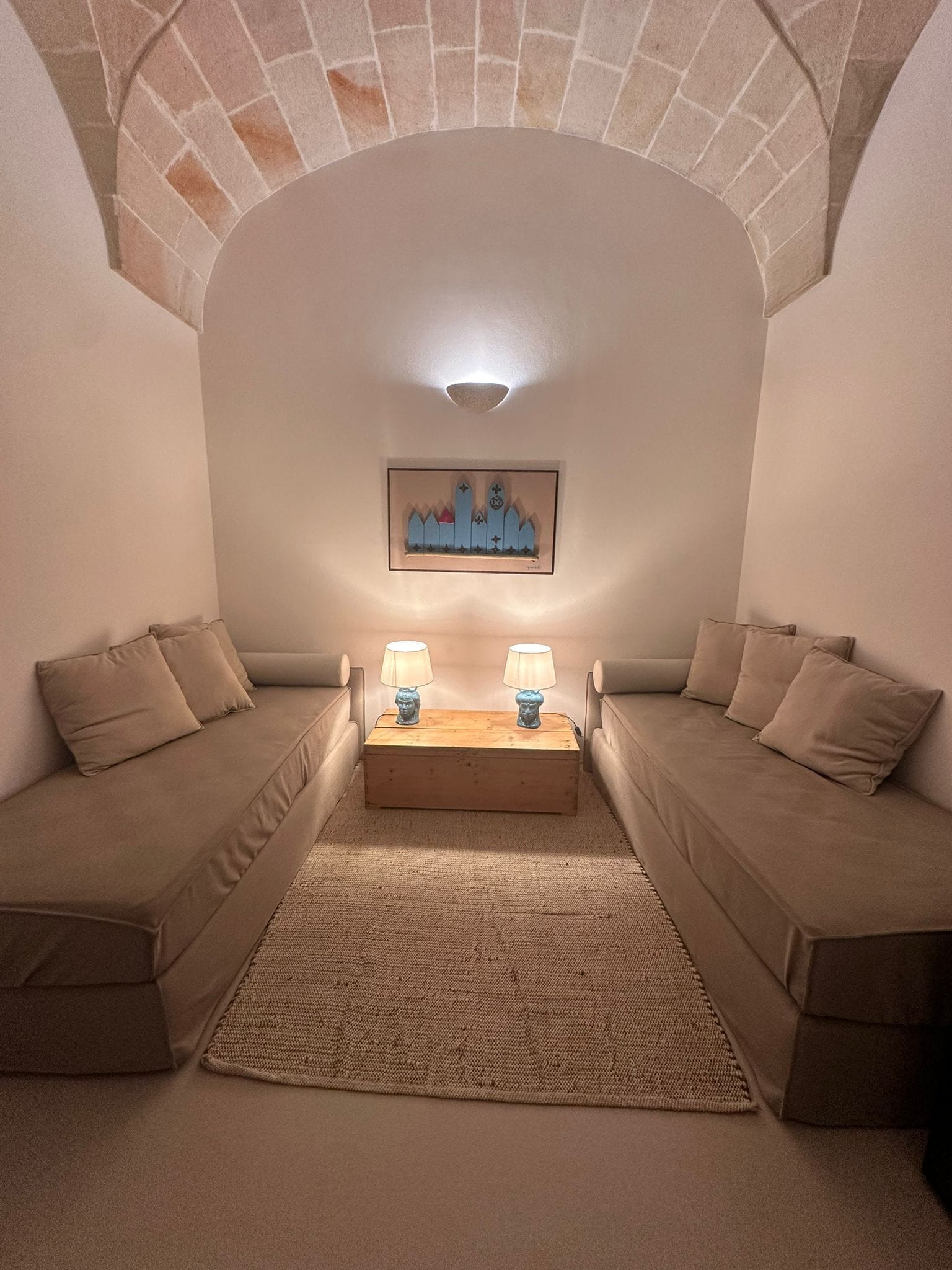 A cozy room with two beige sofas, a wooden coffee table, and a framed cityscape picture on the wall.
