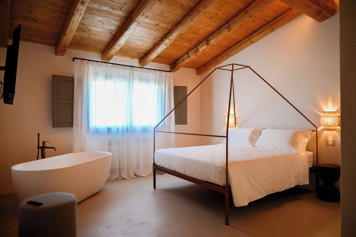 Une chambre à coucher avec un lit à baldaquin, une baignoire sur pieds et une lampe de chevet.