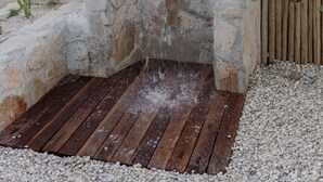Une fontaine en pierre, agrémentée d’une terrasse en bois et de galets.