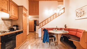 Eine Küche mit Holzausstattung, einem Siemens-Ofen, einer Essecke mit rundem Tisch und einem roten Sofa.