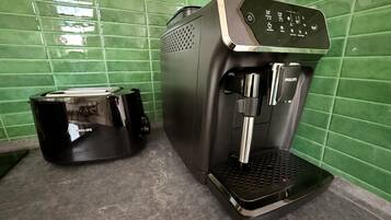 Eine Kaffeemaschine und ein Toaster auf einer Arbeitsplatte mit dunkelgrünen Fliesen.