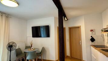 Habitació d'hotel amb llit, escriptori, cadira, televisió i petita cuina.