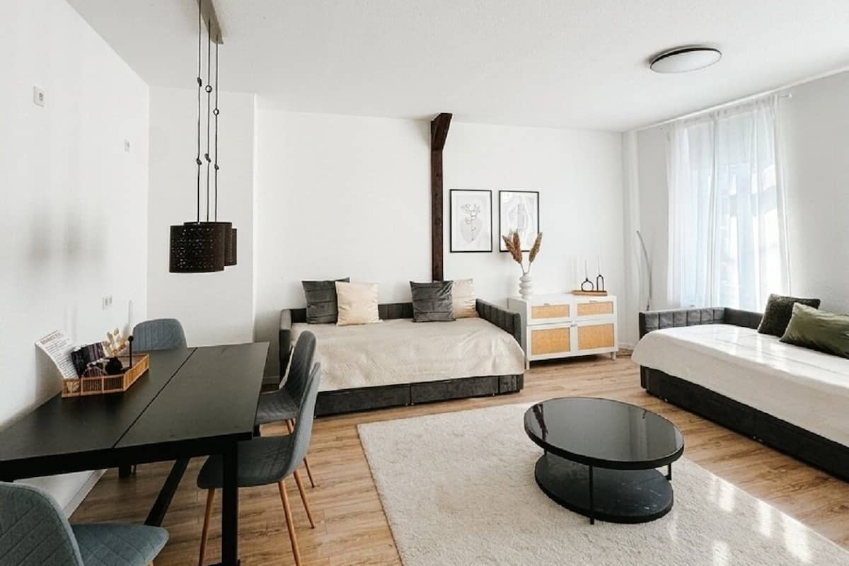 Un dormitorio moderno con cama, sofá, mesa de comedor y una mesa de centro.